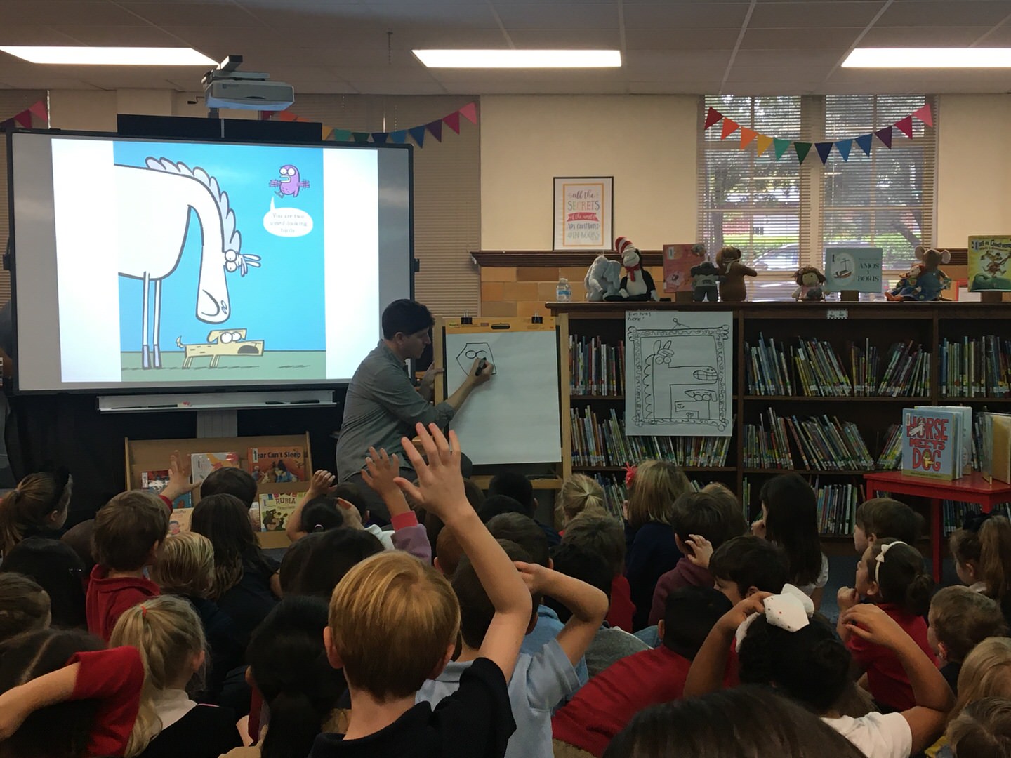 Author Tim Miller illustrating a character from one of his children books to a group of Lily B Clayton Elementary students